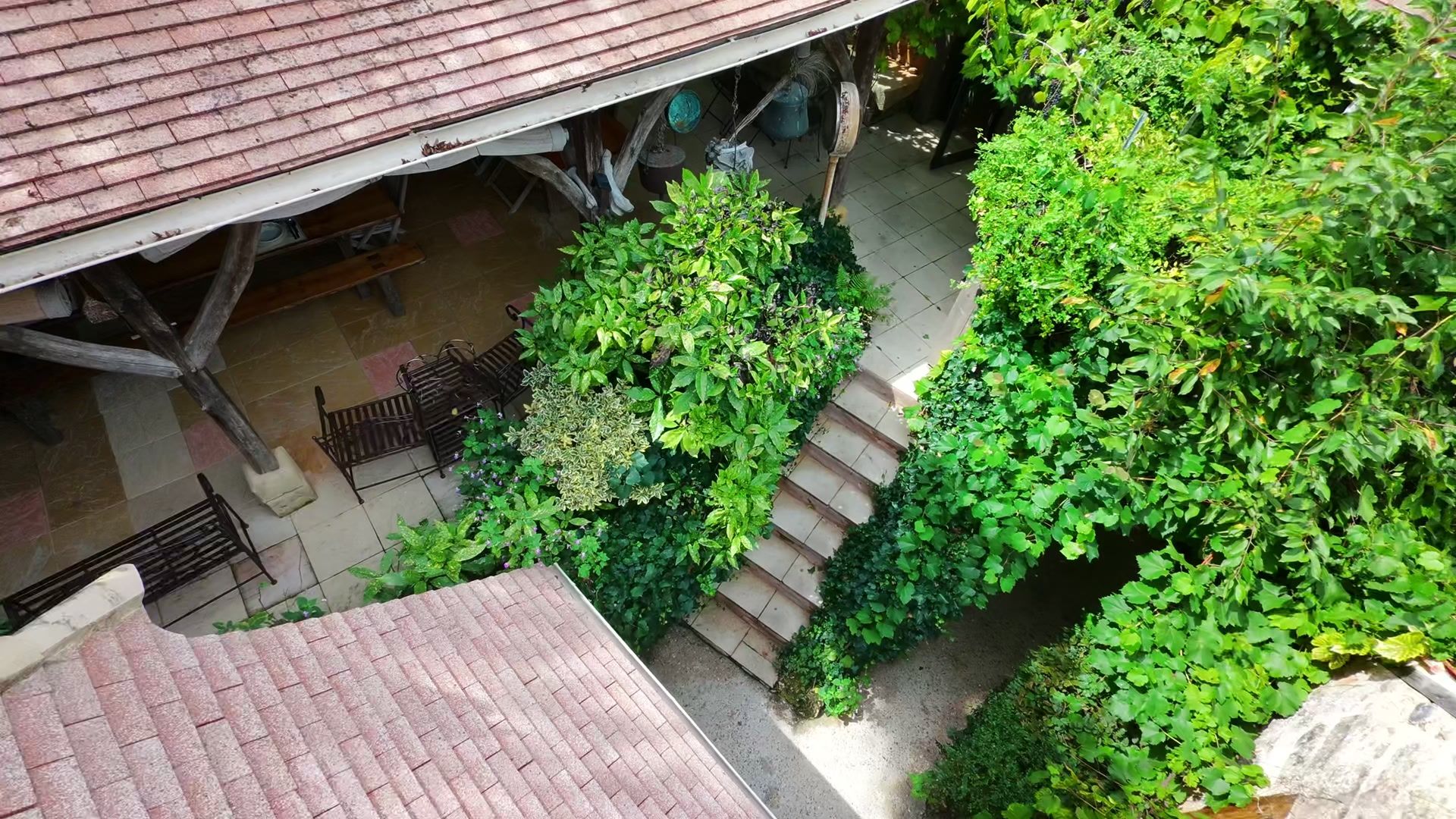 Vue aérienne de l’Auberge de Layotte, ses toits et son jardin nichés dans un vallon boisé du Périgord.