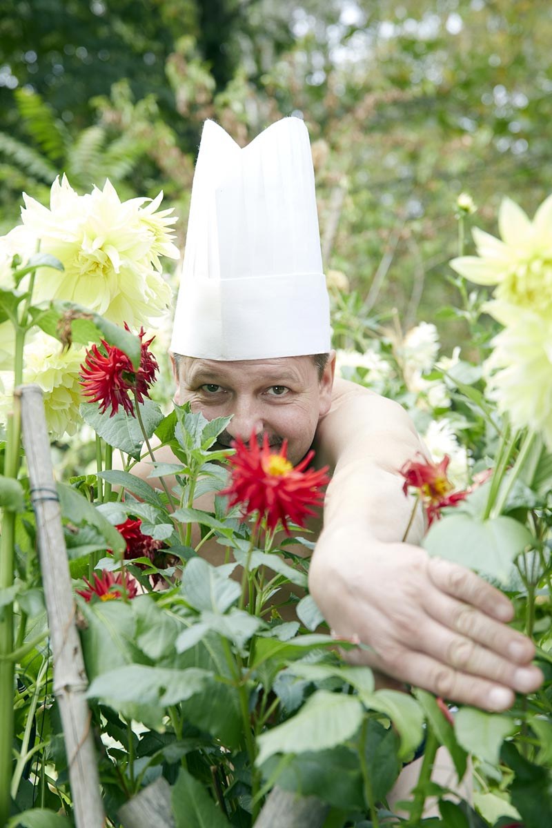 Régis Gagnadre, en toque blanche, au milieu des dahlias du jardin.