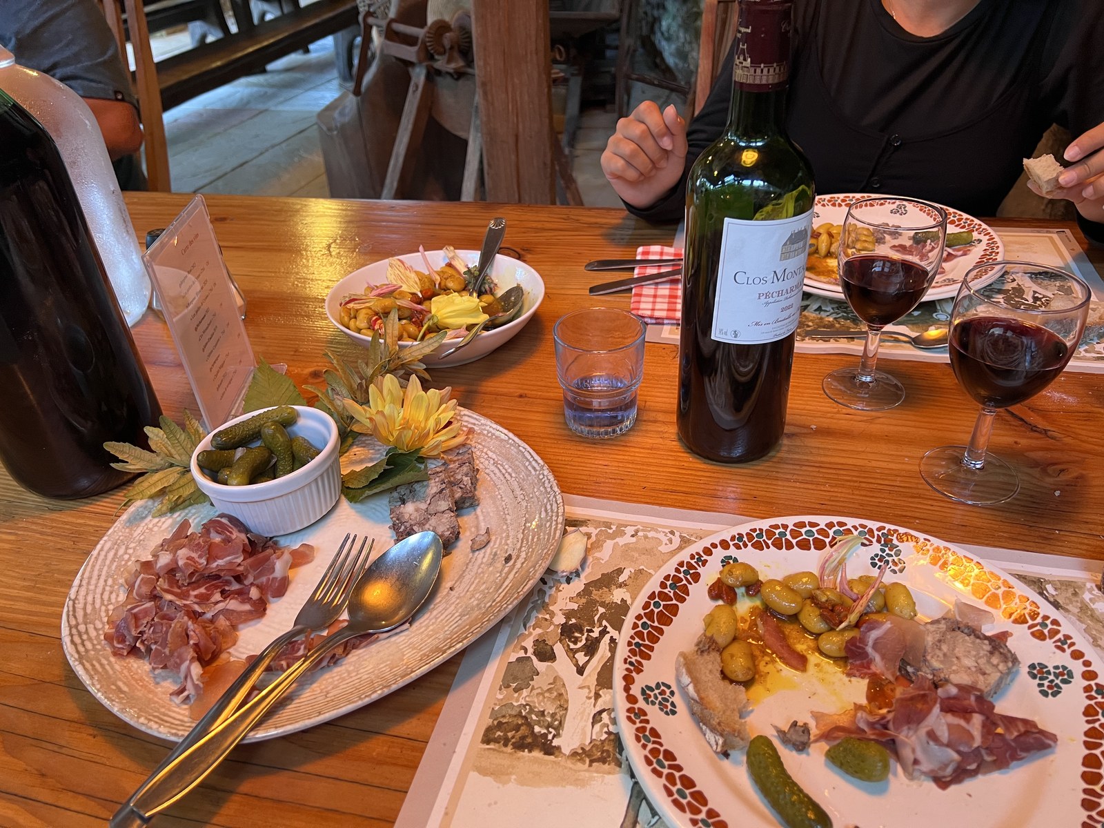 Un repas en cours sur la table de l’auberge : charcuterie, pain et vin.