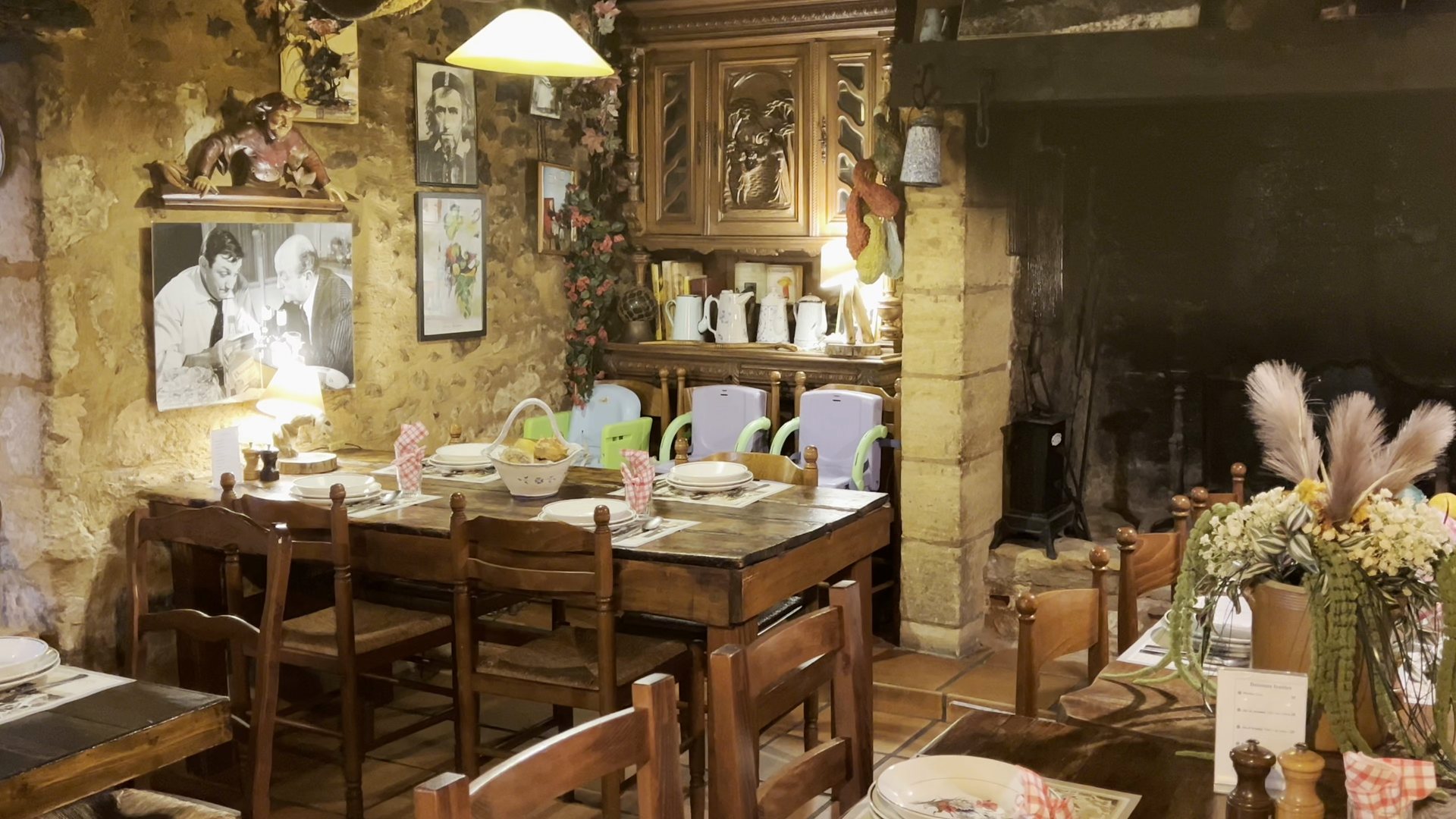 La salle intérieure : la grande cheminée de pierre, le buffet ancien et les tables dressées.